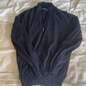 Mörkblå half zip-tröja Sand XL - Mörkblå långärmad tröja från Sand Copenhagen i storlek XL. Tröjan har en snygg half zip-dragkedja och är tillverkad i en mjuk mix av ull, viskos, nylon och kashmir. Perfekt för kyliga dagar och har en klassisk, stilren look.