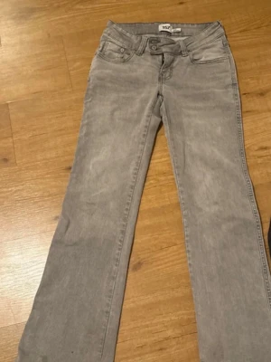Grå jeans med broderade bakfickor - Snygga grå jeans från 157 i storlek XS Short. Modellen har raka ben och klassisk femficksdesign. Bakfickorna är dekorerade med broderade mönster som ger extra stilpoäng. Perfekta för dig som gillar detaljer och vill ha ett unikt plagg i garderoben. Anledningen till att jag säljer den är för att jag gilla inte hur den passa mig.