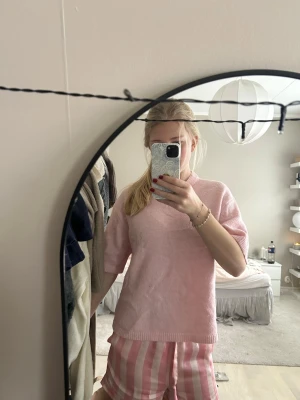 Ljusrosa stickad tröja med kort ärm - Superfin ljusrosa stickad tröja från Bik Bok med korta ärmar och ribbade kanter vid hals, ärmslut och nederkant. Tröjan har en loose passform och är perfekt för vår och sommar. Snygg att styla med jeans eller kjol! Lite skrynklig nu, men stryks vid förfrågan av köp! ❤️❤️