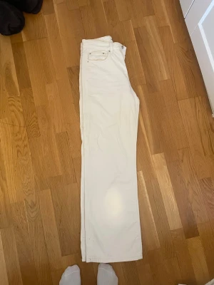 Vita raka jeans med hög midja - Säljer ett par vita jeans med rak passform och hög midja. Byxorna har klassisk femficksdesign och är tillverkade i ett stadigt jeanstyg. Perfekta för dig som gillar en clean och stilren look.