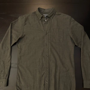 Mörkgrön flanellskjorta Jack & Jones - Säljer en mörkgrön flanellskjorta från Jack & Jones Essentials. Skjortan är i 100% bomull med klassisk krage, knappstängning och bröstficka. 
