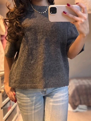 Brun stickad tröja med kort ärm - Säljer en brun stickad tröja med korta ärmar och rund hals. Tröjan har en loose passform och är tillverkad i ett mjukt stickat material som känns skönt mot huden. Perfekt att matcha med jeans för en chill look.