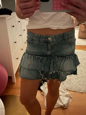 Blå jeanskjol med volanger - Säljer en ass snygg blå jeanskjol med två lager volanger. Skitsnygg till sommaren! Jättebra skick! Från Gina Young! Storlek 158 men passar som xs! 