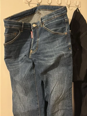 Blå jeans från Dsquared2 - Säljer ett par klassiska blå jeans från Dsquared2 med snygga kontrastsömmar och femficksmodell. Jeansen har en rak passform och är tillverkade i slitstarkt denimtyg. Perfekta för dig som gillar stilrena och tidlösa jeans. Kvitto och tags medföljer
