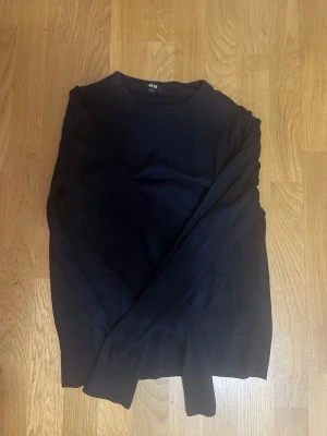 Mörkblå merinoull tröja från Uniqlo - En stilren svart långärmad tröja från Uniqlo i mjuk Merinoull. Tröjan har rund hals och ribbade muddar vid ärmslut och nederkant. Perfekt för lager-på-lager och enkel att matcha med jeans eller chinos. 💪