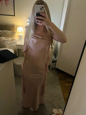 Ljus rosa siden klänning med flowiga volanger💕 - Jag säljer min bal klänning från förra året! Den är i super bra skick och är bara använd en gång, inga fläckar och ser helt ny ut! Den har en perfekt längd på mig som är 167cm lång, alltså stannar den precis vid mina fötter, den är i s, om fler mått önskas så fixar jag det!💕Skriv för fler bilder!