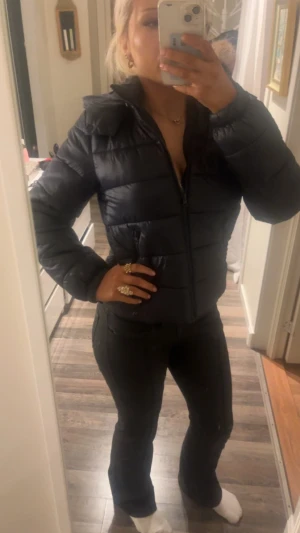 Svart pufferjacka med huva - Säljer en mörkblå pufferjacka från Gina tricot med huva och dragkedja framtill. Jackan har en quiltad design och är lite croppad i modellen, vilket ger en snygg och modern look. Perfekt för kyliga dagar och enkel att matcha med olika outfits. Jag säljer denna då jag ej har haft någon användning för den!! Den har inga skador som ex. Hål repor och sådant 💕