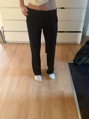 Svarta kostymbyxor med rak passform - Snygga svarta kostymbyxor med rak och klassisk siluett. Dem är ifrån Kappahl och är i storlek 164 (som en Xs).Byxorna har midwaist och är tillverkade i ett slätt material som ger en stilren look. Perfekta till allt