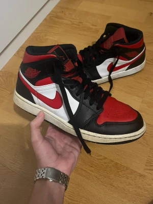 Jordan 1 Mid Storlek 42  - Säljer ett par Air Jordan 1 Mid i den ikoniska svart/röd/vita färgkombinationen. Riktigt snygga sneakers som passar både till vardag och streetwear.  ✔️ Äkta Air Jordan ✔️ Bekväma och stabila ✔️ Normalt använda – se bilder för skick  Skickas snabbt. Hör av dig vid frågor eller fler bilder!