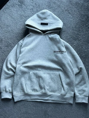 Essential hoodie ljus/grå - Säljer en lightgrey Essential hoodie helt ny kommer med tag som är kvar helt ny oanvänd skön inuti bra material perfekt för en varm tröja😁 