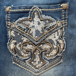 Blå Hydraulic jeans med broderad ficka - Snygga blå jeans från Hydraulic med coolt broderad bakficka i silver och beige, dekorerad med pärlor och mönster. Jeansen har normal passform, klassisk femficksdesign och slitningar framtill för en trendig look.