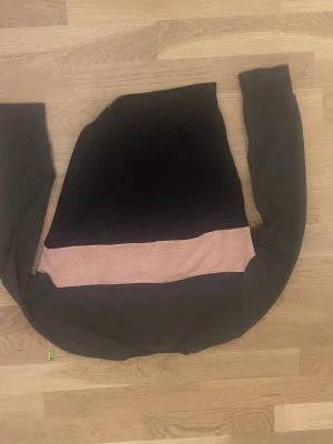 Svart och rosa Adidas sweatshirt S - Cool svart sweatshirt från Adidas i storlek S med bred rosa panel och stor logga framtill. Tröjan har långa ärmar och rund hals. Materialet känns som mjuk bomull och polyester, perfekt för chill eller sportiga dagar.