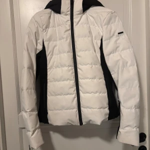 Skidjacka everest intressekoll - Intressekol på min skidjacka. Den ska säljas men måste tvätta den först. Så lägger ut den och tvättar sen. De är en Snygg skidjacka från everest i vitt med svarta detaljer och huva. Jackan har quiltad design, dragkedja framtill och svarta partier längs sidor och ärmar. Perfekt för kalla dagar och skidåkning. Storlek 36. Förutom att den är smutsig så är den i bra skick 
