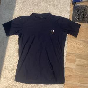 Mörkblå Haglöfs träningströja - Helt ny. Snygg mörkblå t-shirt från Haglöfs i storlek S. Tillverkad i mjuk polyester med klassisk passform och korta ärmar. Diskret Haglöfs-logga i vitt på bröstet. Perfekt för träning eller chill dagar.