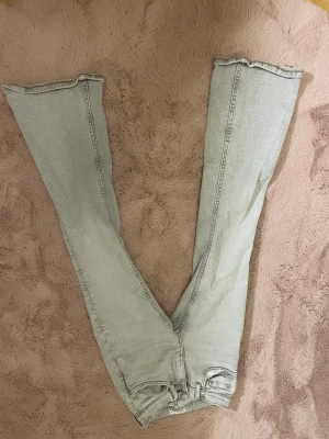 Ljusgrå wide jeans från Gina Tricot - Säljer ett par ljusgrå jeans från Gina Tricot med breda ben och klassisk femficksdesign. Jeansen har normal passform, bälteshällor och dragkedja med knapp. Perfekt för dig som gillar en chill och trendig look.