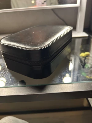 Smyckeskrin med ledljus - Svart smyckeskrin med ledljus. Ljuset har tre lika ljusinställningar och touchskärm. Det finns ett varm, kallt och ett mer neutralt ljus! Laddare roll enheten medföljs! Den har inte använt så den är i nyskick utan några skador. Utsidan av skrinet är läderaktigt.   Fick den i julklapp så vet ej vart den är ifrån exakt.