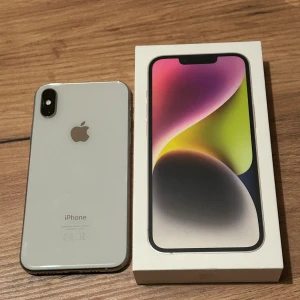 iPhone XS Silver - iPhone XS i silver säljes. Den är i väldigt fint skick och fungerar utan problem. Sitter ett nästan helt nytt skärmskydd på med ”anti-spy”. Vet ej hur mycket lagringsutrymmet som finns och inte hur många procent batterihälsan är på, då jag glömde kolla detta innan den nollställdes. -Liten repa i kameran (inget som påverkar kamerans funktion) -Några sprickor i mobilens egna glas, se bild. -Låda och laddarsladd medföljer.