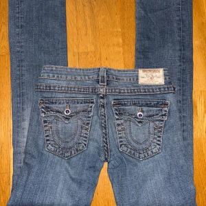 True Religion blå jeans med broderade fickor - Va inte blyga med att pruta eller fråga om mer information. :). Snygga blå jeans från True Religion med ikoniska broderade bakfickor och kontrastsömmar. Modellen har rak passform och klassisk femficksdesign. Jeansen är tillverkade i denim och har en cool vintage-wash. Perfekt för dig som gillar street och premiumkänsla.