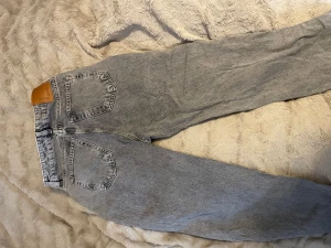 Grå straight jeans från Denim - Snygga grå jeans från Denim med klassisk femficksdesign och raka ben. Jeansen har hög midja, silverfärgade knappar och en ljus tvätt som ger en cool vintagekänsla. Perfekta för dig som gillar en avslappnad och tidlös stil.