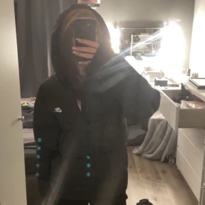 Svart pufferjacka från Nike - Perfekt till vintern. Köpt för 1700 och knappt använd. Säljer en svart pufferjacka från Nike med huva och dragkedja framtill. Jackan har en clean look med diskret Nike-logga på bröstet och är perfekt för kalla dagar. Den är långärmad och har en oversized passform som ger en chill vibe. 