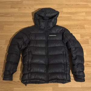 Svart Peak Performance frost down - Svart peakperformence i modellen frost down.Perfekt för kalla dagar. Snygg och funktionell för vintern, nypris 4200kr hör av dig vid fler frågor.