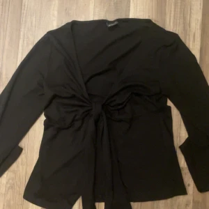 Svart långärmad blus med knyt - Svart blus från Gina Tricot i storlek M. Toppen har långa ärmar och en snygg knytning framtill. Materialet känns mjukt och lätt. Enkel att matcha och passar till många olika outfits.💗💗