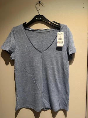 Ljusblå v-ringad t-shirt KappAhl - Snygg ljusblå t-shirt från KappAhl i storlek S. Modellen har v-ringad hals och korta ärmar, 