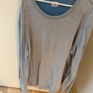 Ljusblå långärmad tröja C.P. Company - Snygg ljusblå långärmad tröja från C.P. Company med rund hals och ikonisk svart linsdetalj på ärmen. Finstickad tröja.