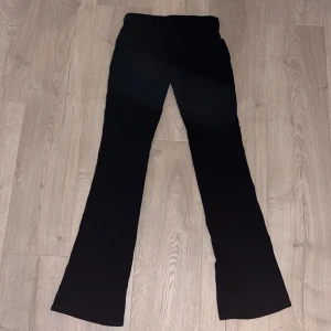 Svarta bootcut mjukisbyxor - Svarta mjukisbyxor med bootcut-modell och låg midja. De har en klassisk och stilren look med utsvängda ben. Perfekta för dig som gillar en enkel men trendig stil. Materialet känns mjukt och stretchigt, vilket gör dem bekväma att bära hela dagen.