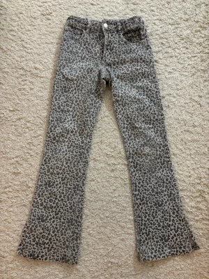 Leopardmönstrade bootcut jeans - Snygga bootcut jeans med leopardmönster i grå och svarta toner. Jeansen har klassisk femficksdesign och normal passform. Perfekta för dig som vill sticka ut med en trendig look.