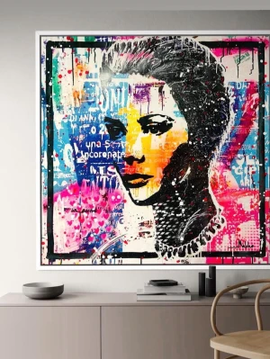 Färgstark popkonst-tavla med porträtt - Unik tavla i popkonststil med ett porträtt i svart, orange och rosa mot en bakgrund av blått, vitt och rosa. Verket har stänkmålade detaljer och textfragment, inramad i svart ram. Perfekt som statement piece i hemmet.