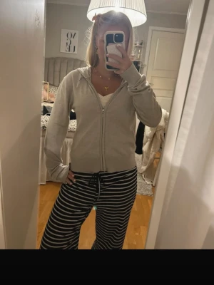 Beige ziphoodie med huva - Säljer en stilren beige hoodie med dragkedja och huva. Hoodien har långa ärmar, ribbade muddar och är perfekt för en avslappnad look. Passar till det mesta och är superenkel att matcha med andra plagg.