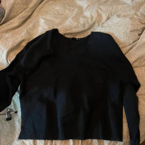 Blå stickad tröja med v-ringning - Säljer en blå stickad tröja från Ivyrevel med v-ringad hals och långa ärmar. Tröjan har en rak passform och ribbstickade muddar vid nederkant och ärmslut. Perfekt att styla med jeans eller kjol.