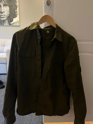 Grön overshirt från C.P. Company - Snygg olivgrön overshirt från C.P. Company. Knappt använd. Skick 9/10. Passar mig som vanligtvis har S-M på kläder! 