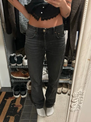 Svarta raka jeans - Snygga svarta jeans med klassisk femficksdesign och raka ben. Jeansen har låg midja och är tillverkade i ett robust jeanstyg som ger en tidlös look. Perfekta för dig som gillar en enkel och stilren stil.