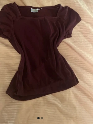 Mörkröd topp med kort ärm - En enkel och stilren mörkröd topp med korta ärmar och fyrkantig ringning. Toppen har en slim passform och är tillverkad i mjukt bomullsmaterial. Perfekt att matcha med jeans eller kjol för en clean look.