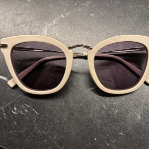 Beige Max Mara solglasögon - Snygga solglasögon från Max Mara med beige bågar och mörka glas. Glasögonen har en klassisk cat eye-form och metallbrygga över näsan. Perfekta accessoaren för soliga dagar.