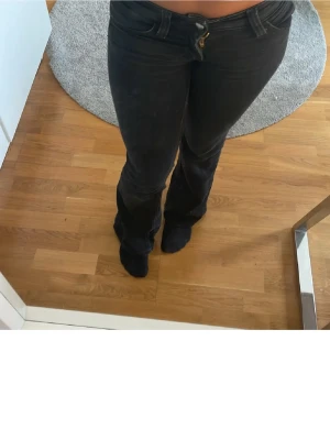 Svarta bootcut jeans med låg midja - Snygga svarta bootcut jeans med låg midja.  Jeansen har en figurnära passform upptill och utsvängda ben, vilket ger en trendig siluett. Tillverkade i ett mjukt och stretchigt bomullsmaterial för extra komfort. storlek 29 och längd 32