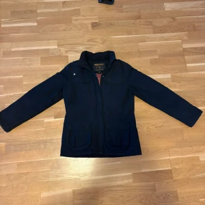 Woolrich field jacket - Säljer en Woolrich field jacket.   Märkt storlek L, men upplevs liten i storleken och passar bäst S/M. Varm dunfyllning, perfekt för höst, vår och vinter.  Nypris cirka 9 000 kr.  Dragkedjan är lite förstörd men tror att det går att lösa ändå, men jackan går fortfarande att stänga och används utan problem. I övrigt är jackan i mycket bra skick.