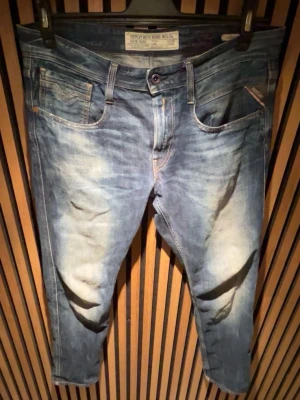 Blå jeans från replay - Snygga blå jeans från G-Star RAW med slitna detaljer och klassisk femficksdesign. Jeansen har en något avsmalnande passform och tydliga tvättade partier framtill och baktill. Perfekta för en avslappnad och trendig stil.
