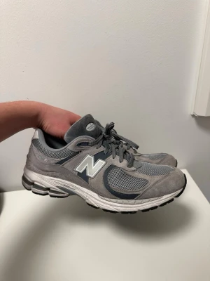 New Balance 2002r skor - Säljer nu dessa new balance 2002r skor införskaffade förra april men köptes i fel storlek och det var redan försent! De har fått ett liten hål där fram, kolla bilder, men går lätt att laga och de har ej används mycket alls! Storlek 45, inget og men har kvitto etc nypris på 1800kr! Skriv gärna vid frågor! 