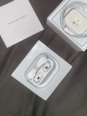 Apple AirPods pro2 trådlösa hörlurar - Säljer ett par vita Apple AirPods pro 2 med laddningsetui. Snygg och kompakt design i blank plast, perfekt för dig som vill ha smidiga och stilrena trådlösa hörlurar. Laddningskabel och originalförpackning ingår.