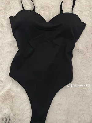 Svart body från Mars The Label - Svart body med smala justerbara axelband. Snygg, figurnära passform. stretchigt och bekvämt. Helt ny med prislappen på!