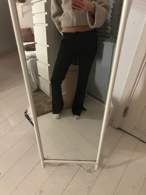 Svarta bootcut kostymbyxor - Snygga svarta bootcut kostymbyxor med klassisk passform och normal midja. Byxorna har en stilren look och passar perfekt till en trendig vardagsstil. Materialet är kostymbyxor och färgen är helsvart.