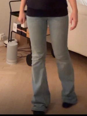 Ljusblå bootcut jeans - Säljer ett par ljusblå bootcut jeans med klassisk femficksdesign och normal passform. Jeansen har en snygg utsvängd siluett och är tillverkade i mjukt denimtyg. Perfekta för dig som gillar retrovibbar och vill ha ett par bekväma jeans. Lite smutsiga och slitna längst ner, men borde gå bort i tvätten (tvättar såklart innan de skickas).