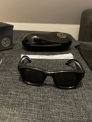 Svarta Ray-Ban solglasögon Wayfarer puffer x asap rocky - Snygga svarta Ray-Ban Wayfarer solglasögon med klassisk fyrkantig form och guldiga Ray-Ban-loggor på skalmarna. Tillverkade i blankt acetat och levereras med originalfodral och putsduk. Perfekta för en cool och tidlös stil.