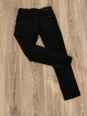 Svarta jeans från Nudie Jeans - Svarta slim fit jeans från Nudie Jeans. Sparsamt andvända. Ett litet hål i högra bakfickan. Jeansen är i storlek w29/L30 Hör av er vid frågor och funderingar!