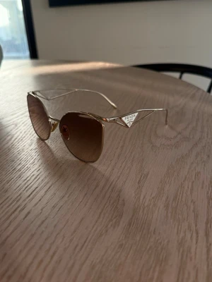 Prada solglasögon med guldiga bågar - Prada solglasögon med guldkant och brunt tonat glas