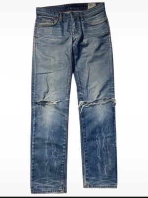 Blå raka jeans från G-Star RAW - Säljer ett par blå jeans från G-Star RAW med raka ben och slitningar över knäna. Jeansen har klassisk femficksdesign, ljus tvätt och coola slitdetaljer.