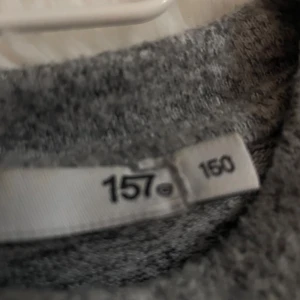 Mörkgrå basic tröja - En enkel och stilren mörkgrå tröja med rund halsringning. Tröjan har en rak passform och är tillverkad i ett mjukt material som känns skönt mot huden. Perfekt att matcha med jeans eller kjol för en avslappnad look. 